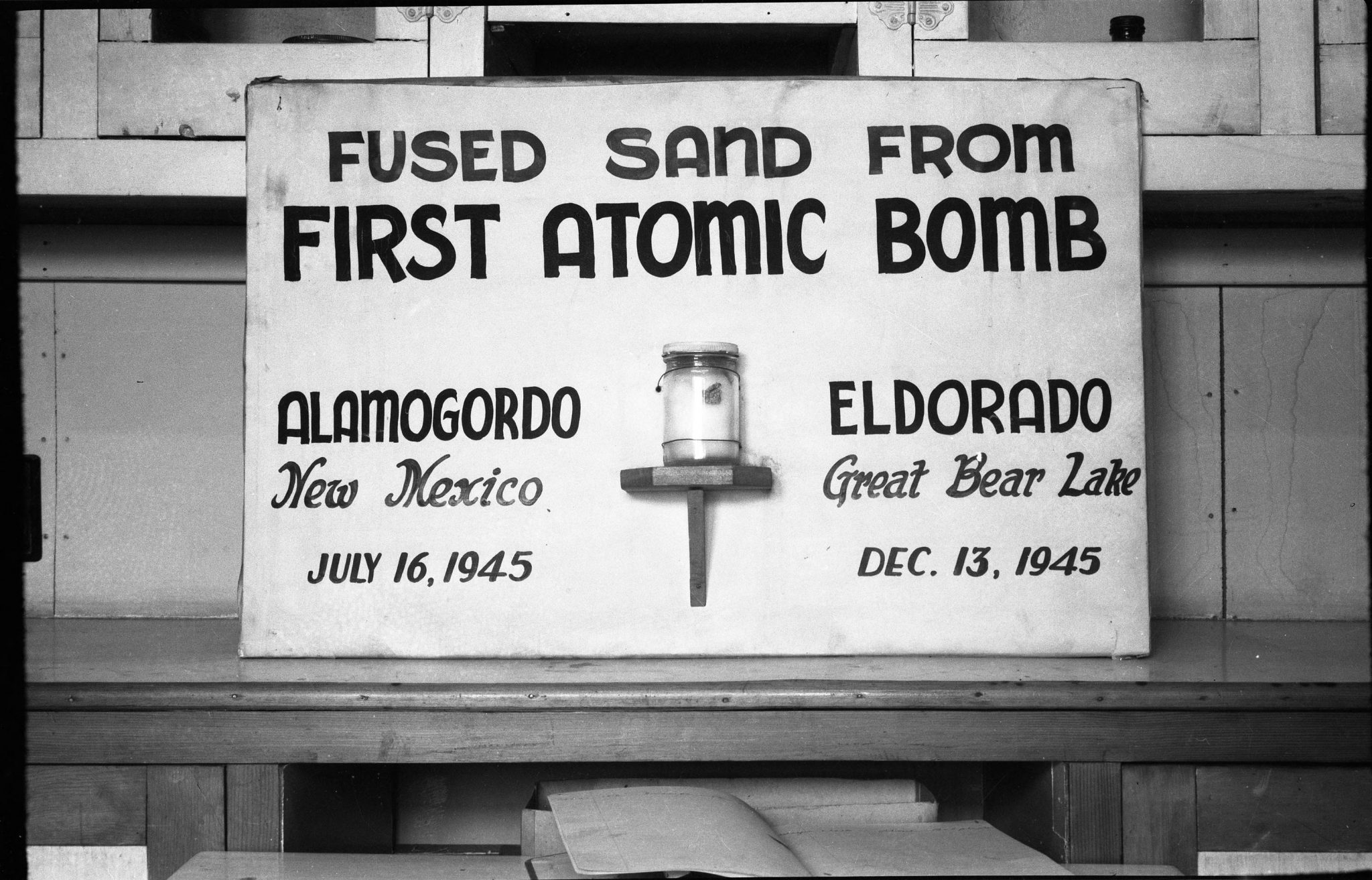 A sign with a jar of fused sand from the first atomic bomb, Alamogordo, New Mexico, July 16, 1945; Eldorado, Great Bear Lake, December 13, 1945 on display in Port Radium. NWT 